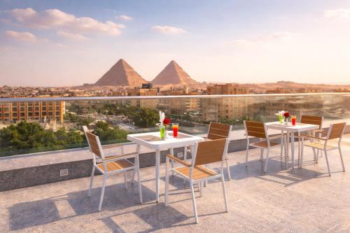 a view of the pyramids from a balcony with tables and chairs at Occidental Cairo Grand Museum in Cairo