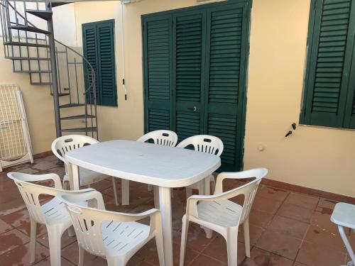 a white table and chairs with green doors at Delfino in Letojanni
