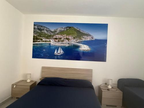 a bedroom with a painting of a sailboat in the water at La Casa Gialla in Cala Gonone