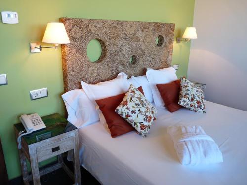 a bedroom with a bed with pillows and a phone at Eco Hotel Boutique & Spa Capitulo Trece - Adults Only in Maderuelo
