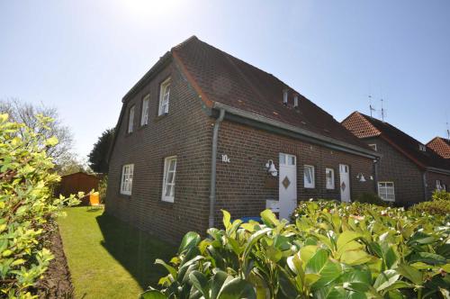 an old brick house with a hedge in front of it at Nr 96 - Ferienhaus Uferstraße in Carolinensiel