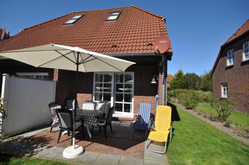 a patio with a table and chairs and an umbrella at Nr 96 - Ferienhaus Uferstraße in Carolinensiel