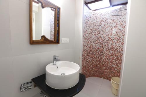 a bathroom with a sink and a shower with a mirror at Raj Residency in Puducherry