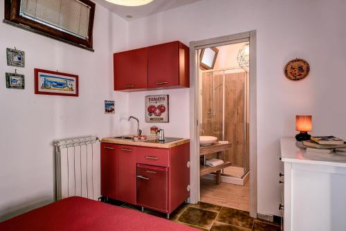 a small kitchen with red cabinets and a sink at Villa Demetra Capri - Pool and Relaxation in Anacapri