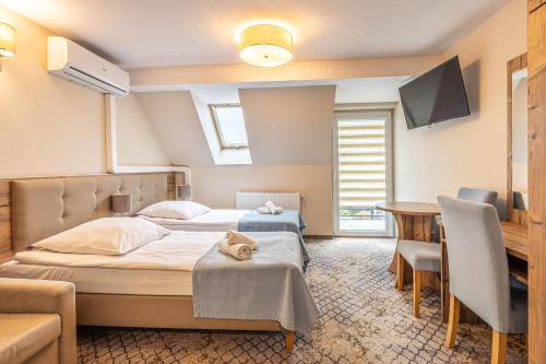 a bedroom with two beds and a table and a tv at Sanatorium Zefir in Krynica Morska