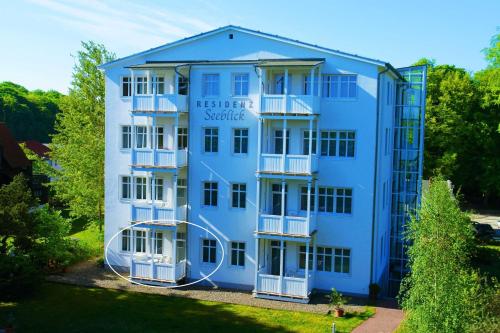 a blue building with white balconies and trees at Residenz Seeblick Whg 4, mit Gartenzugang in Ostseebad Sellin