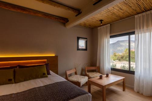 a bedroom with a bed and a table and a window at Alma de Purmamarca in Purmamarca