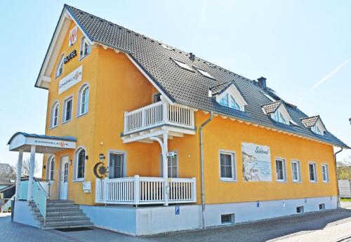 a large orange building with a porch and stairs on it at Hotel Sonnenklahr mit Pool in Göhren