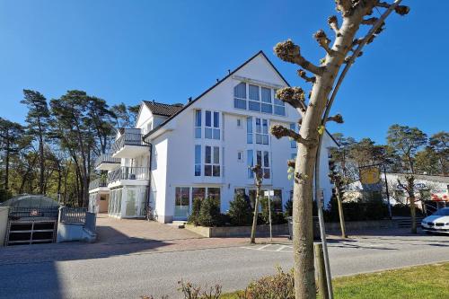 a white building with a tree in front of it at Ferienwohnung Graugans in Baabe