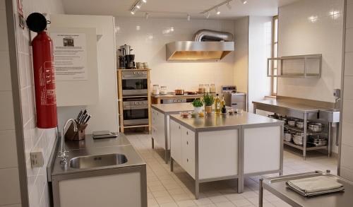 a kitchen with stainless steel appliances and a red fire extinguisher at Le Clos Auvergnat in Tauves