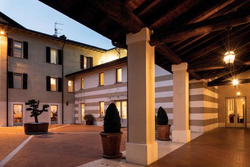 a large building with columns and potted trees in a courtyard at Borgo Santa Giulia in Corte Franca