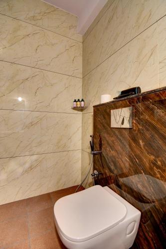 a bathroom with a white toilet and marble walls at AVN Comforts Mysore in Mysore