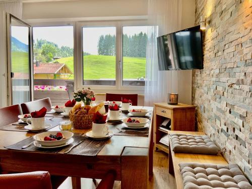 a dining room table with food and a television at Hubertushof in Jungholz