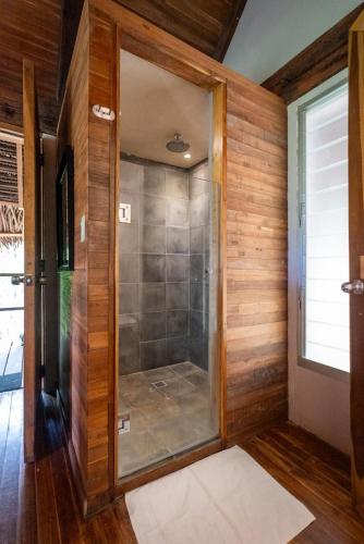 a walk in shower in a room with wooden walls at Eco Venao Lodge, Playa Venao in Playa Venao