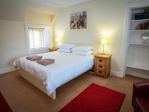 a bedroom with a large white bed with a red rug at Edengrove in Aberfeldy