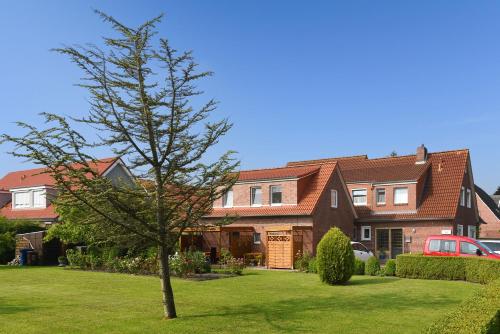 a large house with a tree in the yard at Ferienwohnungen Haus Saathoff in Bensersiel