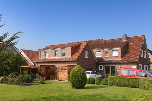 a house with cars parked in front of it at Ferienwohnungen Haus Saathoff in Bensersiel