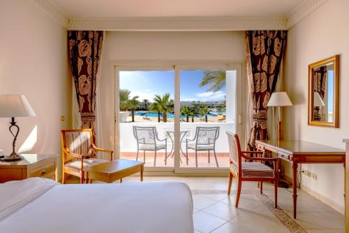 a bedroom with a bed and a desk and a balcony at Continental Plaza Beach Resort in Sharm El Sheikh