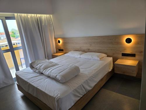 a bedroom with a large bed with white sheets and pillows at Tondoris Apartments in Sidari