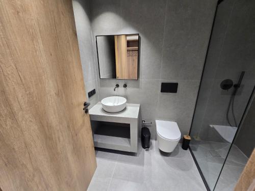a bathroom with a sink and a toilet and a mirror at Tondoris Apartments in Sidari