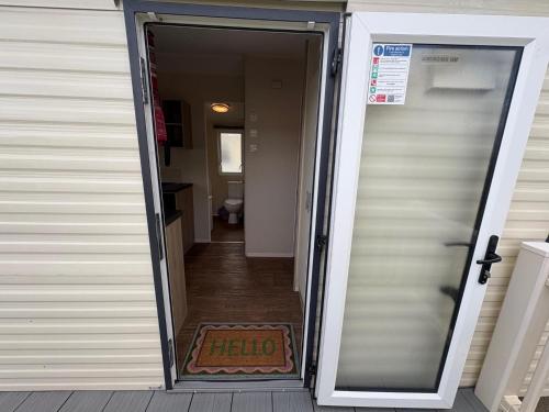 an open door to a hallway with ahate sign on a mat at Prime lakeside caravan at Haven Golden Sands in Mablethorpe