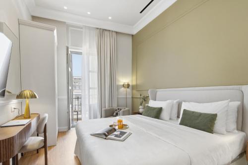 a bedroom with a large white bed and a desk at Hospi Living Empire Suites in Heraklio