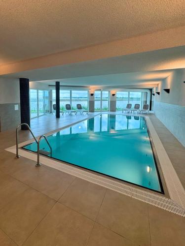 a large swimming pool in a building with chairs at Residenz Bollwark 2 2 in Olpenitz