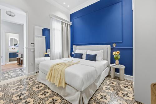 a bedroom with a large white bed with blue walls at Hospi Living Empire Suites in Heraklio