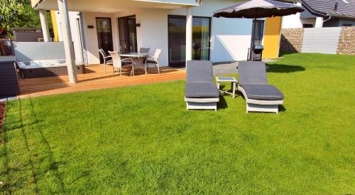 two lounge chairs and an umbrella on a lawn at VILLA AQUILA _ EG_Fewo in Göhren-Lebbin