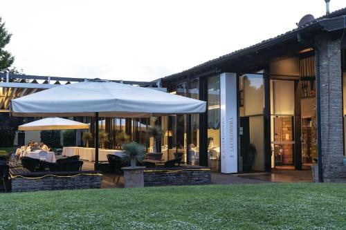 a patio with an umbrella and tables and chairs at La Colombera Ristorante - Albergo in Castrezatto