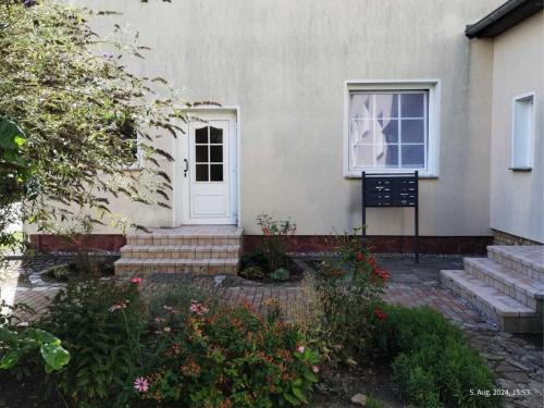 a house with a white door and some flowers at Peene Alte Schule Völschow Dornberger in Völschow
