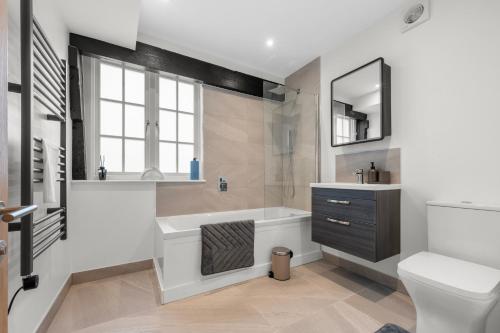 a bathroom with a tub and a sink and a toilet at Modern & Historic Duplex Flat Riverside in Godalming