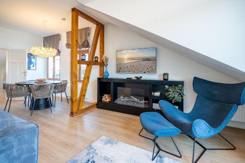 a living room with a fireplace and a blue chair at Villa Linquenda App 6 in Ahlbeck