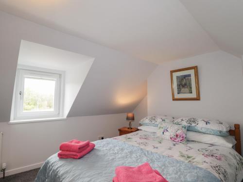 a bedroom with a bed with pink towels on it at 3 Bruaich Cottages in Strathpeffer
