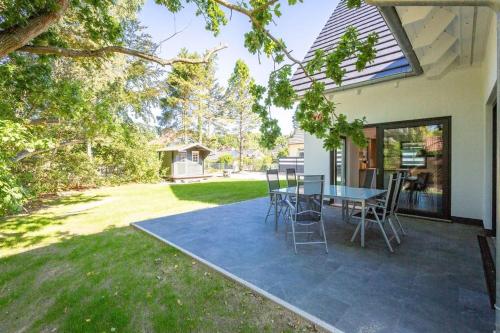 a patio with a table and chairs in a yard at Ferienhaus an der Küsteneiche in Koserow