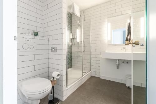 a white bathroom with a toilet and a sink at Holiday Inn Calais - Centre Car Ferry by IHG in Calais