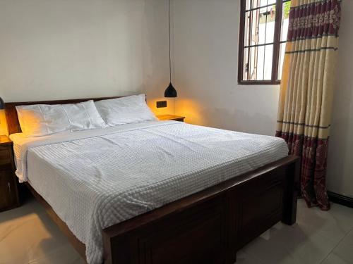 a bedroom with a bed with white sheets and a window at Mulberry Villa in Anuradhapura