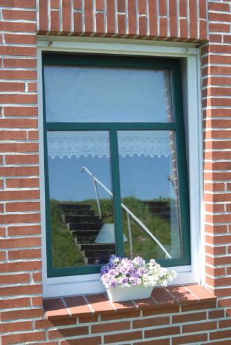 a window with a pot of flowers on a brick wall at Ferienwohnung Nachbars Garten in Grünendeich