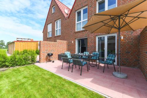 a patio with a table and chairs and an umbrella at Ferienhaus Ella in Dornumersiel