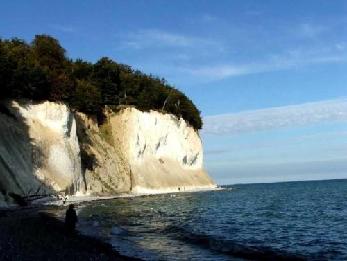 a person standing on a beach next to a large cliff at Appartements Villa Drachenberg in Sassnitz