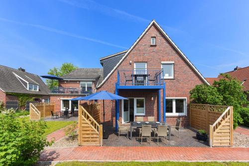 a house with a patio with a table and chairs at Ferienwohnungen Blaues Haus in Bensersiel
