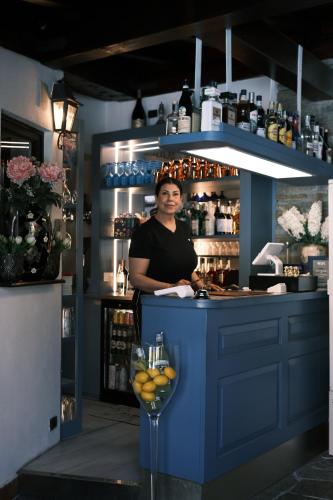 a woman standing at a counter in a blue kitchen at Hotel Sonenga in Menaggio