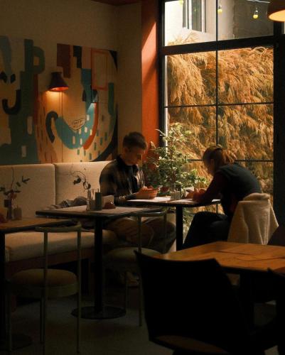 two people sitting at tables in a restaurant at Artifact Apart Hotel in Tbilisi City