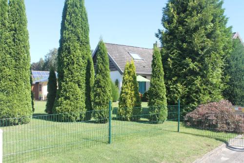 a fence in front of a house with trees at Thiessen - Ferienwohnung mit sonnigem Balkon in Silberstedt