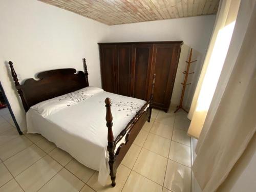 a bedroom with a bed and a wooden cabinet at Quinta da Ana, Casa de Roça in Baependi