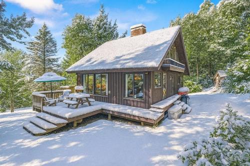 a small cabin with a snow covered roof in the snow at Smugglers Trove a Mountain Adventure Getaway in Cambridge