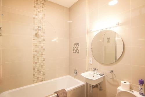a bathroom with a tub and a sink and a mirror at Apartments @ 125 in Gaborone