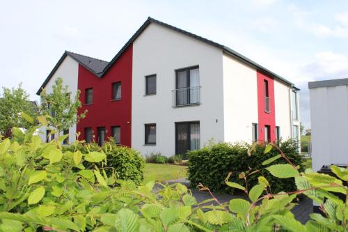 a red and white house with bushes in front of it at Villa Grande Fewo Enjoy We 2 in Göhren-Lebbin