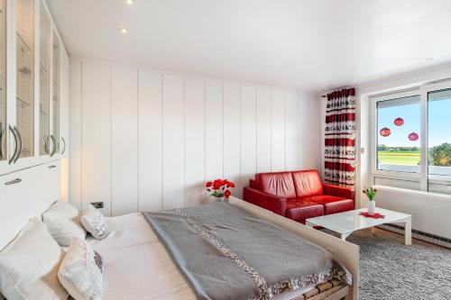a bedroom with a large bed and a red chair at Apartment Korthals 42 in Wangerland