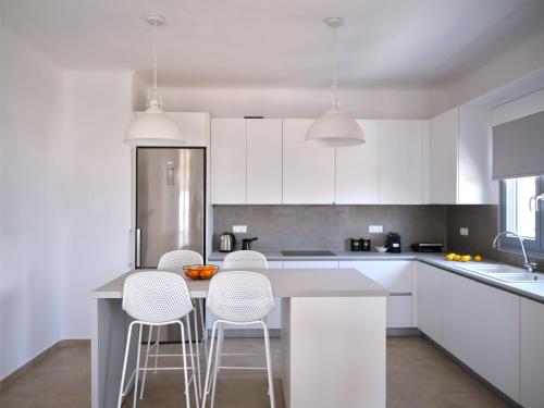 a kitchen with white cabinets and a table with stools at Mouragio Stay - Aliki , Paros in Aliki